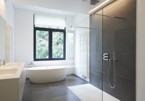 Bathtub in corian, Faucet and shower in tiled bathroom with windows towards garden