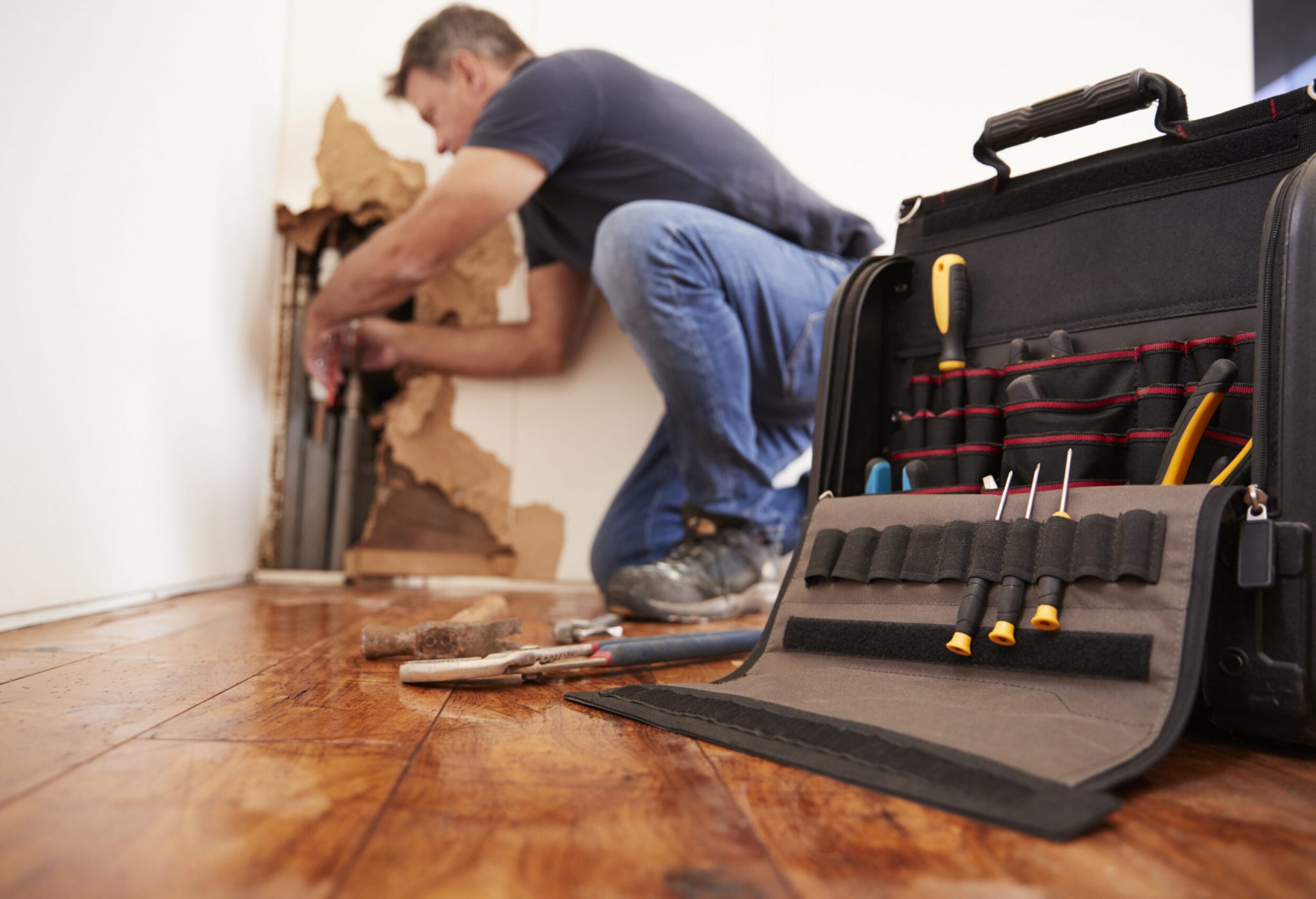 Middle aged man repairing burst pipe,plumbing, focus on foreground